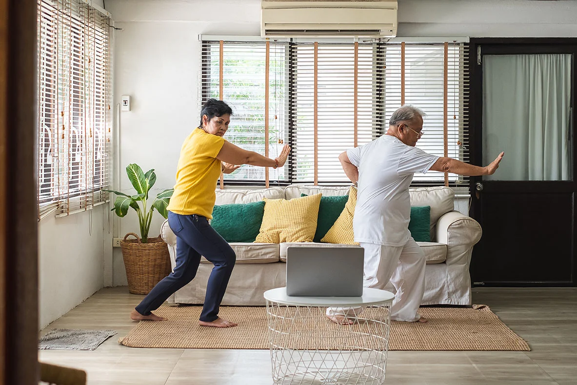 Two adults practicing Tai Chi movements at home